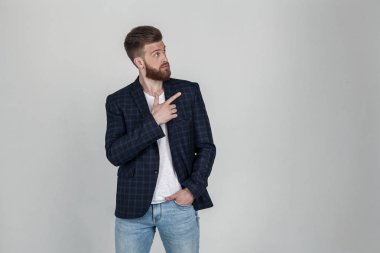Pozitif genç erkek freelancer veya blogger iş sonuçlarından memnun olmak, samimi hoş bir gülümseme var, ön parmak ile yukarı puan, ceket giyer, beyaz duvara karşı stüdyoda duruyor