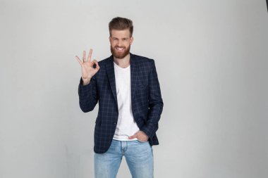 yakışıklı gülümseyen iş tamam jest gösteren. ceket giymiş. gri arka plana karşı pozlar. yüz ifadesi, duygular.