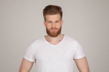 Beyaz tuğla duvar arka plan üzerinde izole kamera isteyen ciddi düşünceli erkek Kızıl sakallı, kayıtsızca, giyinmiş