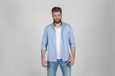 O beyaz bir arka plan önünde duruyor rahat giysiler giymiş güzel seksi sakallı adam