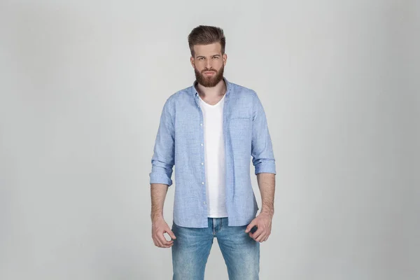 Hermoso hombre barbudo sexy vestido con ropa casual se pone delante de un fondo blanco — Foto de Stock