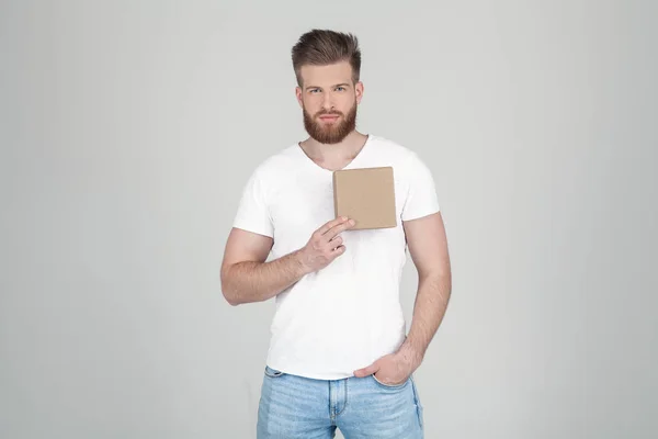 Hombre exitoso con barba de jengibre exuberante. sostiene una caja con un regalo en el corazón. un lugar para un logotipo o una inscripción vestida con ropa casual. pie frente al fondo blanco — Foto de Stock