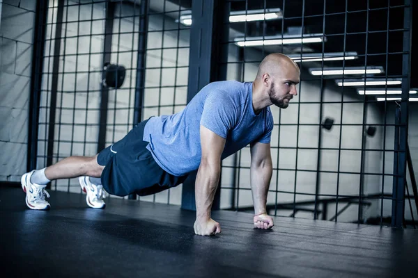 Force et motivation. Vue latérale de jeune homme chauve beau en tenue de sport faisant push-up à la salle de gym — Photo