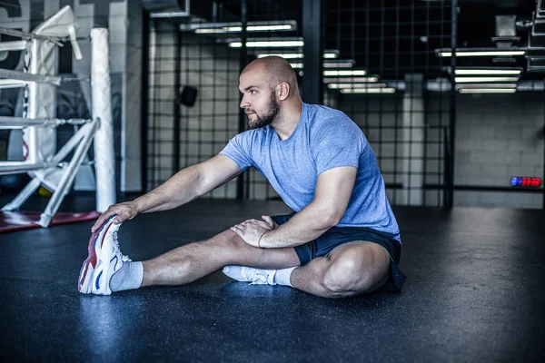 Jeune homme préparant les muscles avant l'entraînement. Athlète musclé faisant de l'exercice au gymnase. Prêt à s'étirer. Réchauffement sportif professionnel. Portrait intégral. habillé en uniforme de sport . — Photo