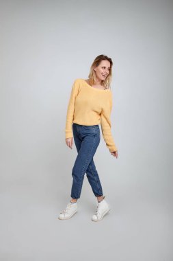 şık giysiler giymiş güzel bir sarışın, tam uzunlukta bir portre. beyaz arka plan önünde pozlar