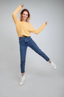 Aktif iyimser kız stüdyoda fotoğraflandı, beyaz arka plan üzerinde havada atlar, geniş bir gülümseme vardır, şık giysiler giymiş. Hareket benim hayatım.