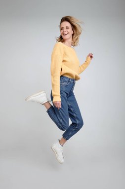 Onun sarı saçlı elleri ile bayan Tam bacaklar vücut boyutu portre kenara o parlak beyaz arka plan izole rahat kıyafet giymek kadar atlamak