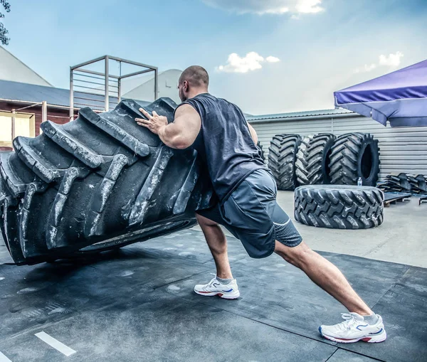 Vue arrière de l'homme de remise en forme musclé fort mouvement gros pneu dans la salle de gym de rue. Levage de concept, entraînement — Photo