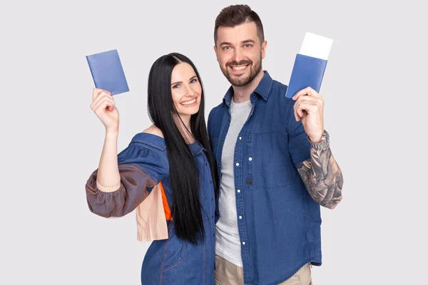 Portrait de joyeux couple heureux tenant un passeport avec des billets d'avion dans les mains regardant la caméra isolée sur fond gris vif — Photo