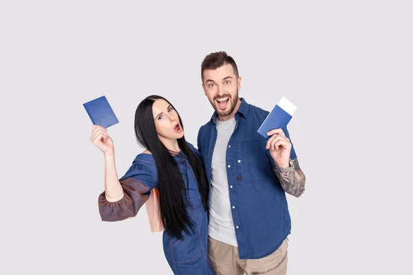 Portrait de joyeux couple heureux tenant un passeport avec des billets d'avion dans les mains regardant la caméra isolée sur fond gris vif — Photo
