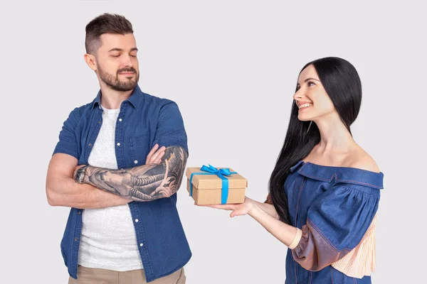 Outraged guy. The girl gives a gift to the guy who is offended by her. dressed in casual clothing. stand in front of a gray background