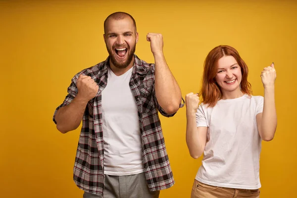 We can do it. Successful team of coworkers clench fists, celebrate victory, exclaim positively, looks confident, have cheerful faces, isolated over yellow background. People, success and triumph