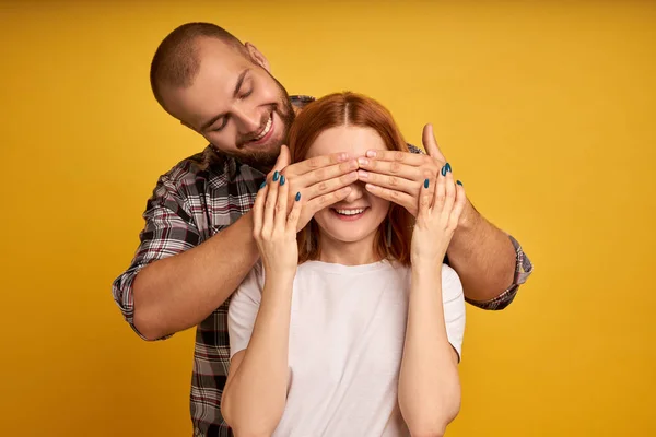 Excité jeune couple joyeux debout isolé sur fond jaune, couvrir les yeux, surprise — Photo