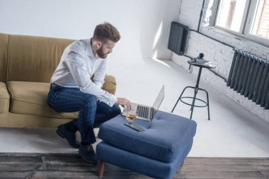 Sakallı hipster çocuk profesyonel serbest sosyal medya içerik yazar dizüstü bilgisayarda klavye yaparken coworking alanda oturuyor. Adam yetenekli metin yazarı netbook üzerinde promosyon içerik yazarak