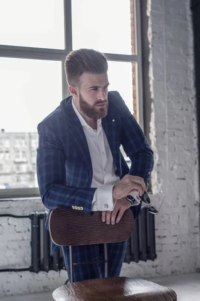 For god til å være virkelig. En kjekk, ung mann i dress som ser bort mens han sitter på krakken. – stockfoto