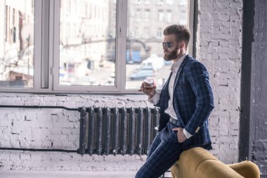 Bir şey düşünüyorum. Tam takım elbise li ve güneş gözlüklü düşünceli genç adam viski içiyor ve kanepeye yaslanarak elini cebine koyarak uzaklara bakıyor..