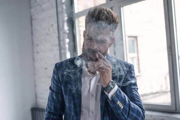 Un retrato de un hombre maduro guapo con un traje formal fumando un cigarro en el interior. Belleza de los hombres, moda . —  Fotos de Stock