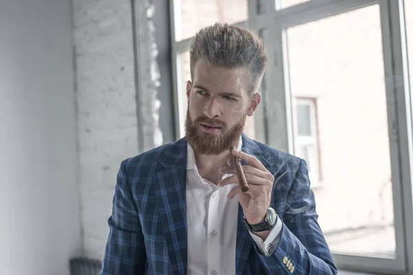 Un retrato de un hombre maduro guapo en un traje formal fumando un cigarro en el interior. Belleza de los hombres, moda . —  Fotos de Stock