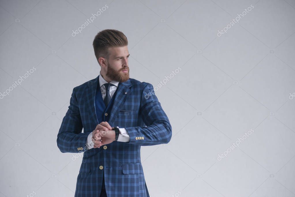 Young bearded stylish businessman leader indoors at office wearing sunglasses with watch looking aside serious