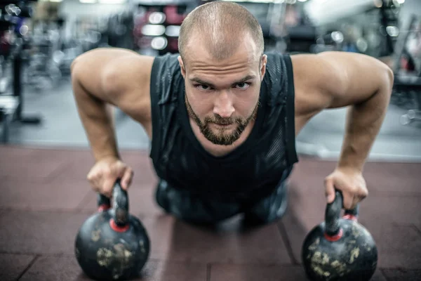 Όμορφος μυώδης άνθρωπος κάνει push ups σε κέμπμπωλ σε διασταύρωση γυμναστήριο — Φωτογραφία Αρχείου