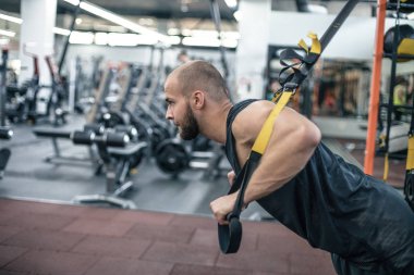 Trx eğitimi. Spor salonunda Trx Excersise yapan cross fit eğitmen. Halkalar üzerinde Fitness adam egzersiz. Spor salonunda fitness adamı. Fitness tarzı. Halkalar üzerinde egzersiz. Spor ve zindelik. Crossfit egzersiz