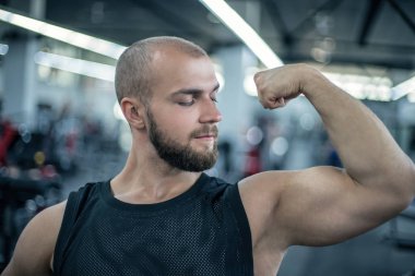Yakışıklı güçlü atletik adam kasları egzersiz vücut geliştirme kavramı arka plan kadar pompalama. Vücut geliştirmeci kaslar gösteren, pazı ve triceps. yumruklarla kollarını esneme.