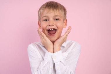 Güzel rüya gibi sürpriz şaşırmış çocuğun pembe arka plan üzerinde izole kamera bakarak yanakları dokunmadan Closeup fotoğraf portresi