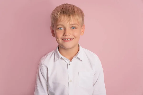 Портрет счастливого веселого милого улыбающегося мальчика, держащего руки скрещенными. студийный портрет на розовом фоне. Место в джинсах и белой рубашке . — стоковое фото