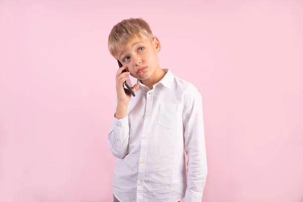 Портрет грустного школьника говорить по телефону, у него плохие новости на розовом фоне, белая рубашка, деловая тема . — стоковое фото