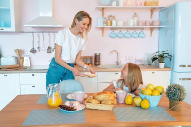Mutlu anne kızına kahvaltıiçin çörek getirdi. mutlu aile kavramı. Mutfakta birlikte eğlenin