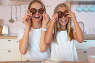 Mutlu bir aile. Anne ve onun sevimli küçük kızı gözleri ve gülümseyerek çikolatalı kurabiye tutarak selfie yaparken eğleniyoruz.