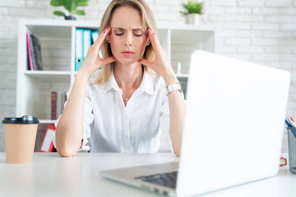 young attractive sad and desperate businesswoman suffering stress and headache at office laptop computer desk looking worried depressed and overwhelmed in business problem concept