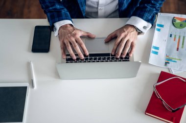 İnternette gezinirken not defterine not alan ve çevrimiçi verileri analiz eden genç yönetici veya çalışanın üst görünümü
