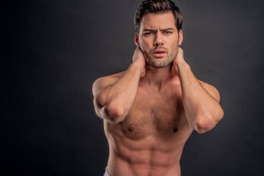 Yakışıklı, sakallı adam izole edilmiş. Üstsüz, havlulu kaslı adam gri arka planda duruyor. Ciddi adam kameraya bakıyor.