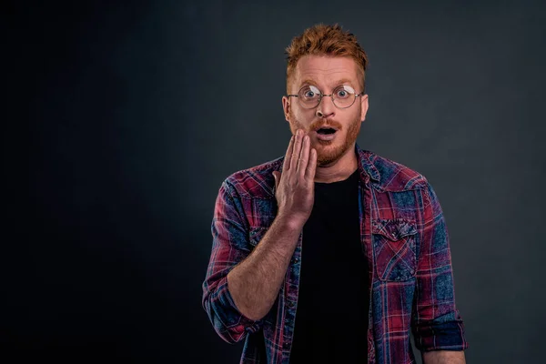 Insecure cute redhead man in glasses did not expact kiss in cheek from loving woman on date, touching face and staring surprised and amazed at camera, opening mouth and widen eyes