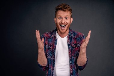 Şaşkınlık ve şaşkınlık içinde gülen adam, piyango kazandığına inanamıyor, avuçlarını kaldırıyor, gülümsüyor ve kıkırdıyor, mutluluk ve sevinçten şaşkına dönüyor..