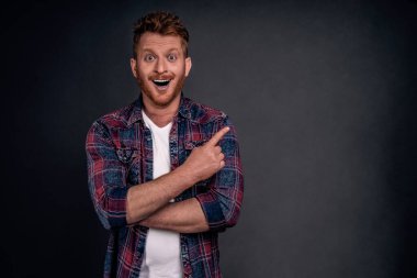 İnanılmaz robotlar gören bir adam, çocuk gibi şaşkın ve mutlu. Gözlüklü ve tişörtlü yakışıklı Avrupalı erkek portresi, neşeyle gülümsüyor, sağ üst köşeyi işaret ediyor..