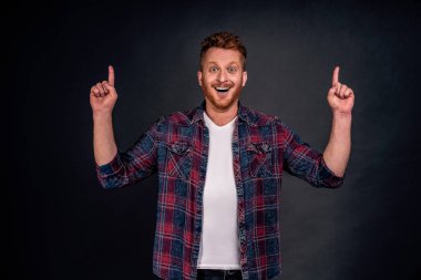 Gururla yukarı doğru büyük bir konsept gösteriyor. Güzel görünüşlü, kendine güvenen ve mutlu Avrupalı adamın portresi. Tüylü, el kaldıran ve mutlu bir ifadeyle işaret eden, kendini harika hisseden..