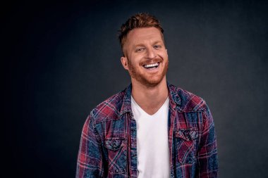 Neşeli, hoş görünümlü, kızıl saçlı, mavi tişörtlü, neşeli beyaz bir adam. Geniş bir gülümseme, ilginç ve komik bir sohbet. Dostluk çemberindeki güzel bir partide rahatlıyor..