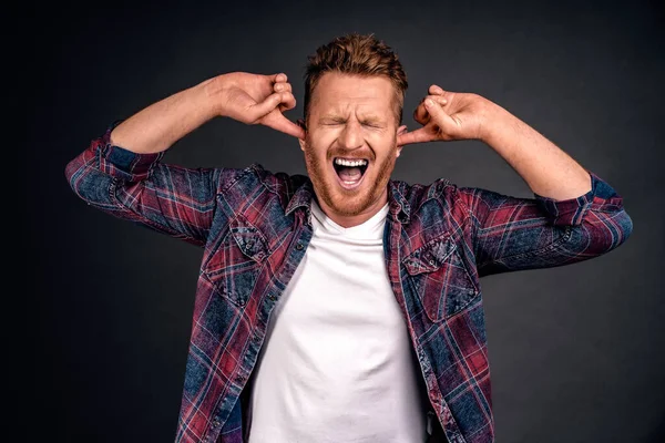 Kapat şu gürültüyü. Gıcık ve hoşnutsuz, günlük kıyafetlerle tüylü, kulaklarını işaret parmağıyla kapatan, kulak tıkacı gibi kaşlarını çatan ve burnu rahatsız edici sesten kırışan çekici kızıl bir adam..