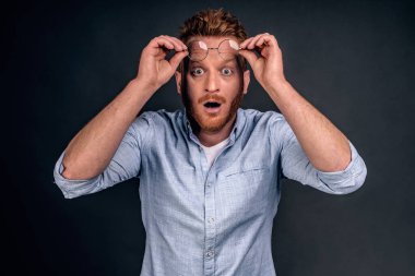 Gözlüklerini çıkaran adam inanılmaz ve hayret verici bir sahne görüyor, dudaklarını katlıyor, alnında gözlük tutuyor ve kameraya bakıyor sanki gri arka planda bir mucize görüyormuş gibi..