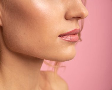 Pembe arka planda izole edilmiş yumuşak, dolgun dudakları olan çekici, çıplak bir kızın yarı yüz portresini kapatın. Fotokopi alanı, sağlık, sağlık sigortası, reklam konsepti..