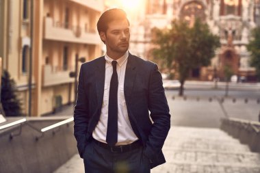 Genç ve başarılı. Dışarıda dikilirken takım elbiseli yakışıklı bir genç.