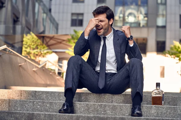Anxious businessman sitting in steps. Stressed businessman headache and look down with depress feeling. Business problems, Fired, Unemployed, bankrupt due to covid-19
