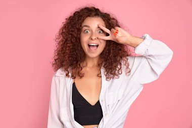 İyimser, tatlı, iyimser, kızıl saçlı kız. Barışçıl zafer jestini gösterirken eğlenin. Disko işareti yapın..