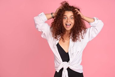 Saçlarına dokunup kameraya gülümseyen güzel kızıl kızın portresi. Pembe arkaplan