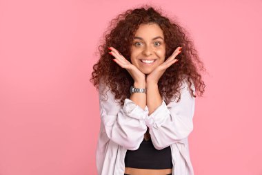 Kadınlar süper mutluluktan sakinleşemezler. Çekici, neşeli, kızıl saçlı kız arkadaş pozitif duygulardan parlıyor, yüzün yanında el ele tutuşuyor, şaşkınlıktan çenesini indiriyor, pembe duvarın üstünde heyecanlanıyor..