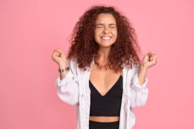 Mutluluğun gerçek renklerini gösteren pozitif kızıl saçlı kadın. Güzel genç kız öğrencinin portresi, pembe duvarda gülüyor ve sevinçten uçuyor..