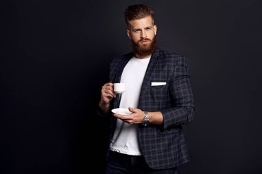 Şık, yakışıklı, gerçekten çekici, rüya gibi zengin, zarif bir adamın portresi. Siyah arka planda izole edilmiş taze acı kahvenin kokusunu kokluyor.