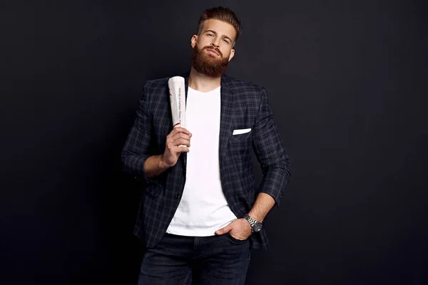 Confident businessman with a ginger beard stands on a black background with a newspaper in his hands.